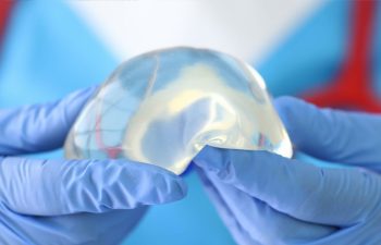 Doctor holds silicone implant in gloves.
