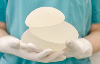 Plastic Surgeon holding breast implants