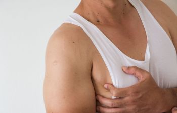 Man in a with vest touching his breast