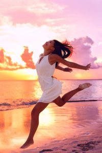 Happy young woman dancing on a beach.