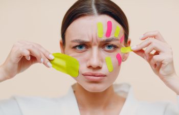 A woman taping face to achieve the effect of facelift.