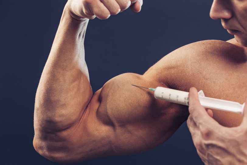 Bodybuilder injecting steroid shot into his biceps.