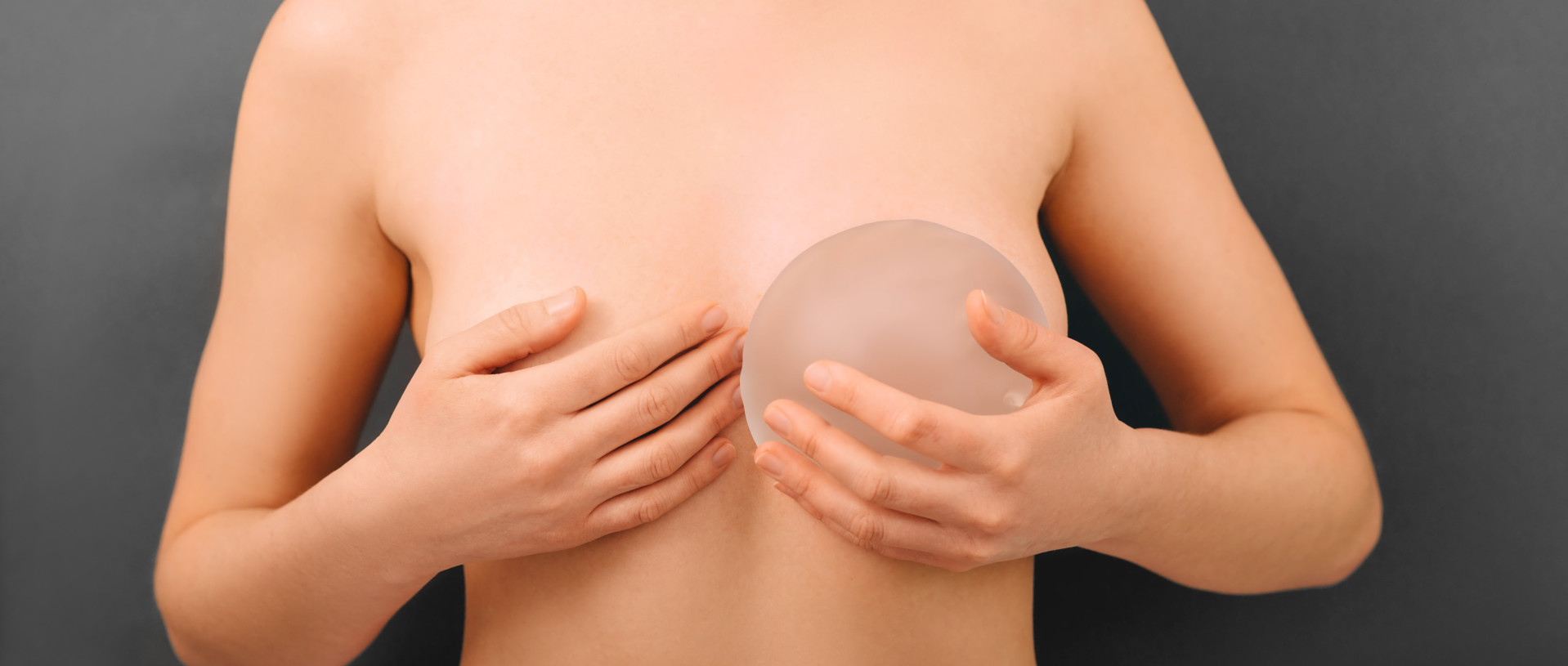woman holding breast silicone implants near the breast