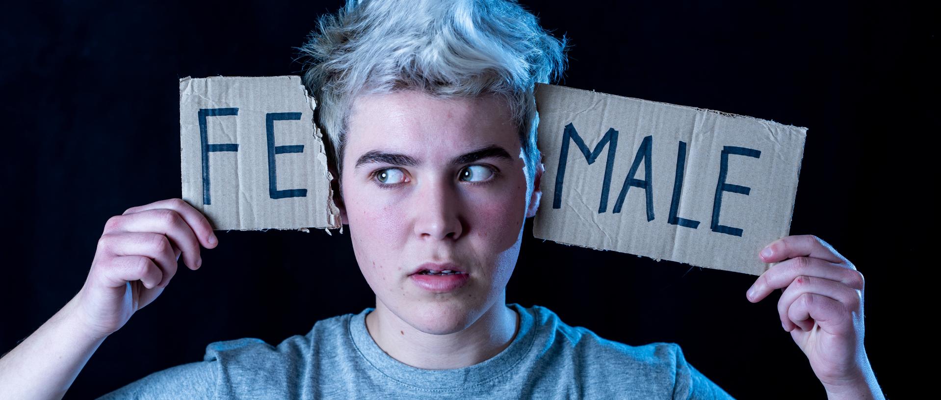 handsome transgender teenager tearing the word female into male in gender identity