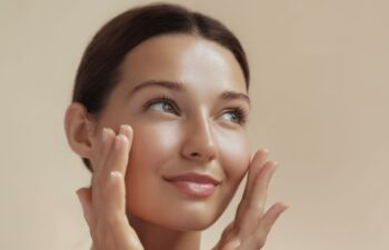 Woman after facial rejuvenation with fat transfer touching her cheeks