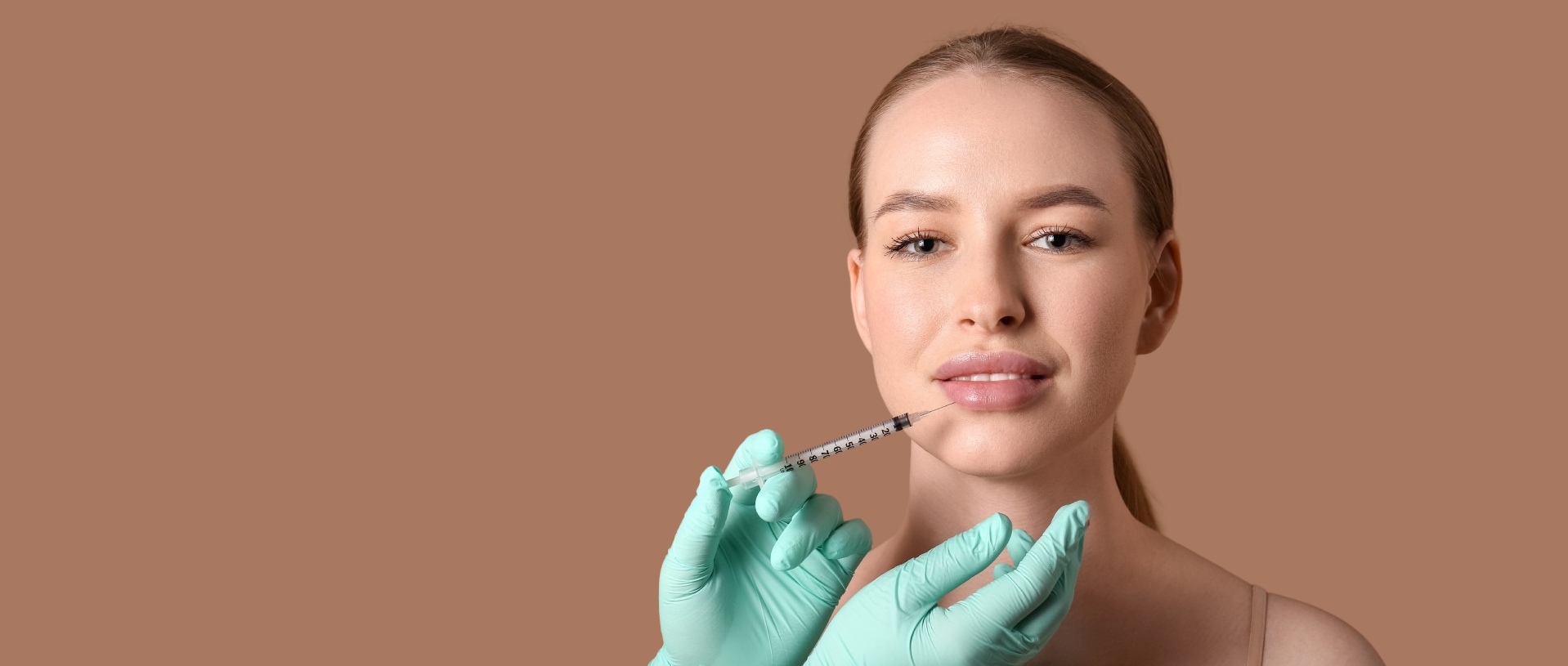 beautiful young woman receiving filler injection in lips