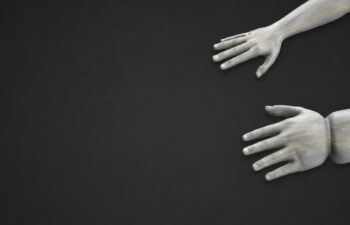 Two human arms extended on a dark background with yellow lines illustrating nerves running through the wrists and hands.